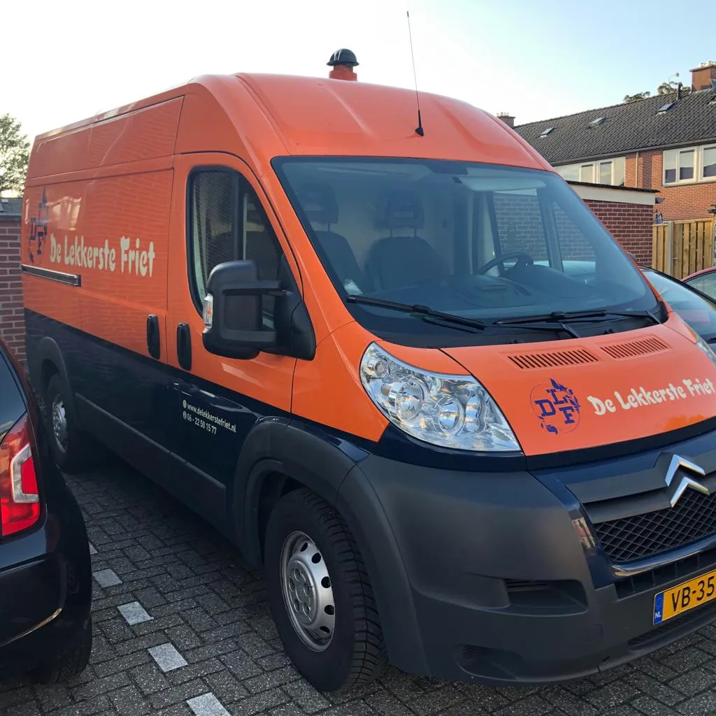 Voertuigbelettering op de oranje bestelbus van De Lekkerste Friet door ZON Reclame.