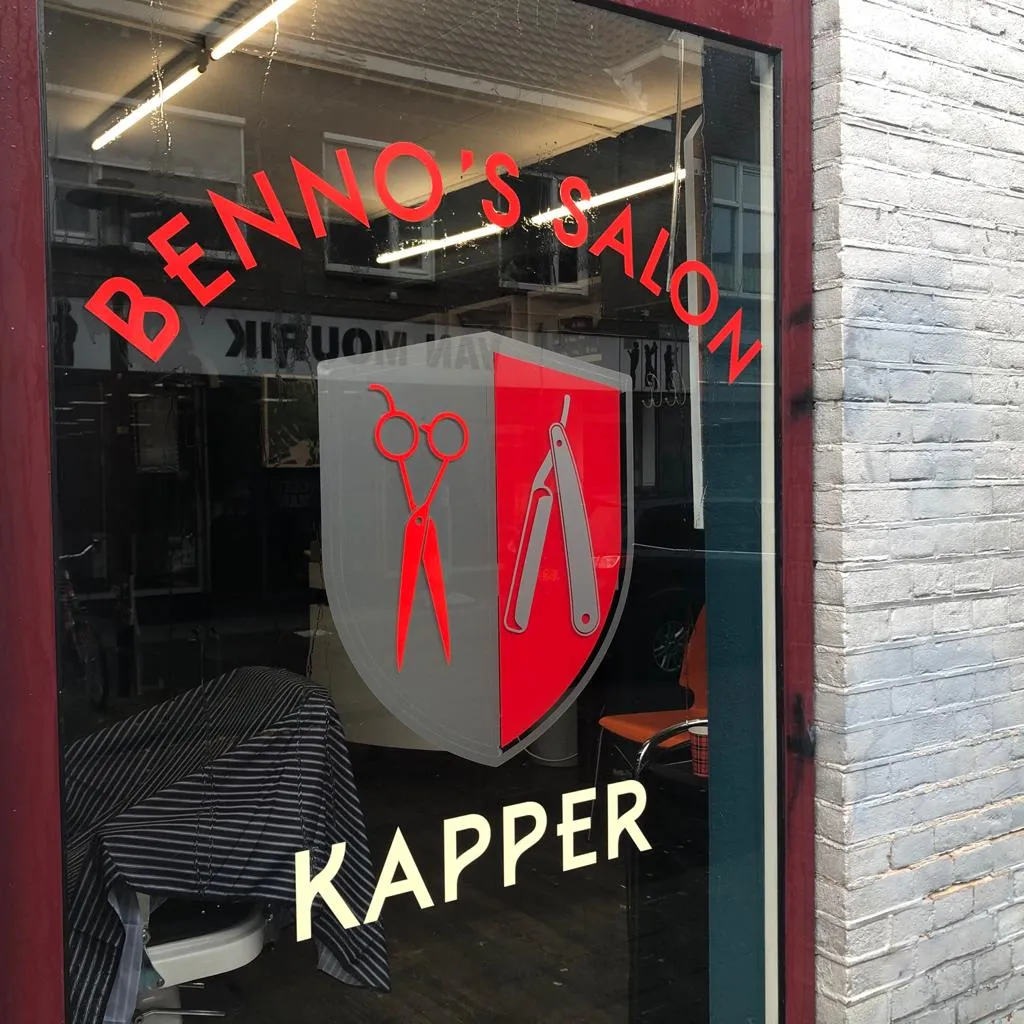 Rode raambelettering met schaar-en-mes-wapenschild voor kapper Benno's Salon door ZON Reclame.